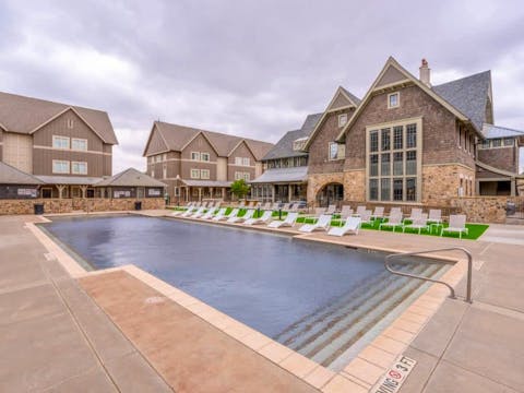 The-Collective-at-Lubbock-Off-Campus-Cottage-Apartments-Pool-with-Lounge-Chair-Seating-on-Turf-Grass-Resident-Clubhouse-Building-Exterior-1000x667